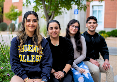 Four students sit on a bench and smile