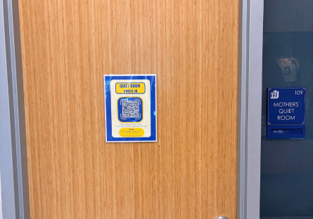 Image of Hannelly Center Lactation Room Door with a blue and yellow sign that reads "Quiet Room Check-in" with a QR code and a blue sign next to the door with the Phoenix College logo, the number 109 and words "Mothers Quiet Room"