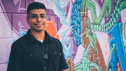 Mural artist Edgar Fernandez stands in front of his vibrant artwork, Cosmic Consciousness (2017). Photographed by Diego Nacho.