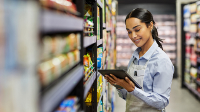 A grocery store staff holds a clipboard in the grocery aisle. 