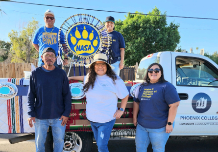Phoenix College student Melvin Pastores (upper left) stands in a Phoenix College truck decorated for the parade with Phoenix College students and staff 