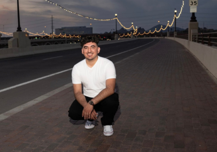 Phoenix College Nursing student Victor Salinas on a bridge smiling; he is recipient of the Equality Maricopa PRISM Scholarship
