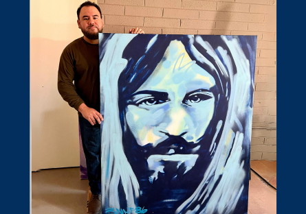 Francisco Garcia in his Grand Avenue studio standing behind a large canvas of his work.