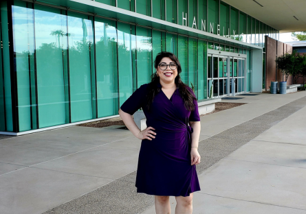 Athena Sanchez stands in a blue dress in front of the Hannelly Center at Phoenix College