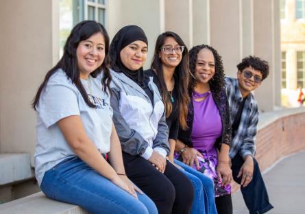 Sally Alsigab, second from left, sits outside Fannin Library with other students during a campus photo shoot. 