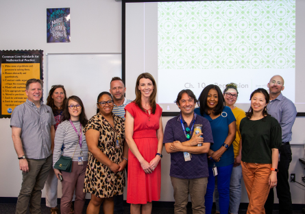 Marcia Corby (Distinguished Teacher Honoree 2024) posing for photo in her math class with faculty