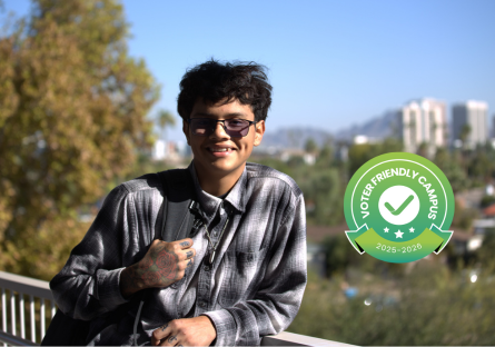 student standing at Physical Sciences building with voter friendly campus seal