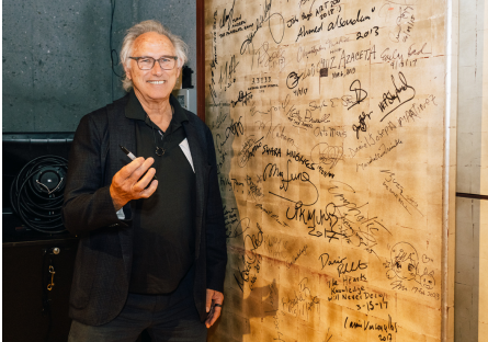Artist and Phoenix College Alumnus Eric Fischl stands next to the artist signature wall on campus