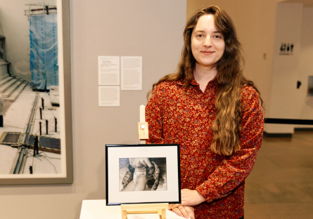 Phoenix College art student Lila Castenada stand next to her photograph, "Lady in Waiting," which won a 2025 Vanguard award