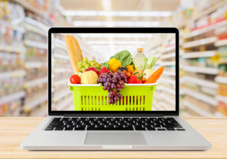 a laptop in the aisle of a grocery story showing a basket of food