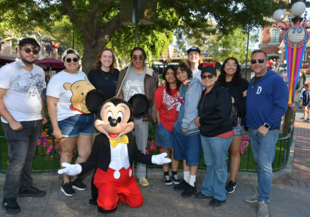 Phoenix College honors students take a picture with Mickey Mouse at Disneyland with Program Director Kenny Miller and Program Advisor Safia Sampson