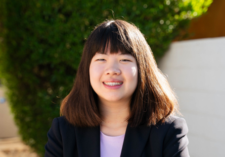 Headshot of Olina Fong on campus with a white background and triangle of green foliage behind her