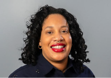Headshot of Pamela Smith with shoulder length curly black hair and bright red lipstick