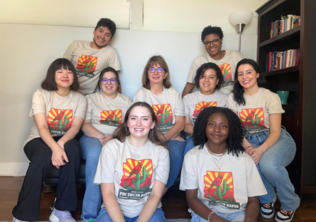 Olina sits on the left of the regional officers of PTK during a retreat.  They are all wearing the same PTK beige t-shirt with the outline of the state of arizona with a cactus and a bird inside image. 