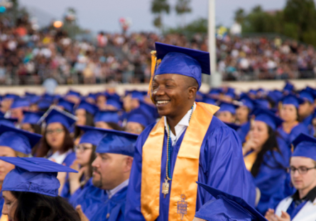 Isaac Batu in commencement regalia standing up to be recognized by graduates at 2016 graduation