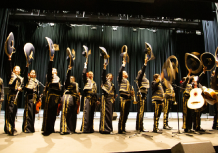 Phoenix College's Mariachi Ensemble dressed in traditional trajes hold their sombreros in the air 