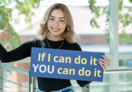 Jasmin in the Dalby Building holding up a sign that states, "If I can do it YOU can do it"