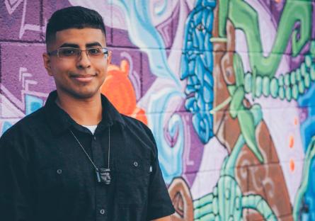 Mural artist Edgar Fernandez stands in front of his vibrant artwork, Cosmic Consciousness (2017). Photographed by Diego Nacho.