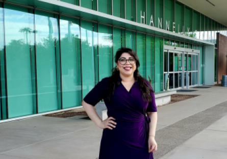 Athena Sanchez stands in a blue dress in front of the Hannelly Center at Phoenix College