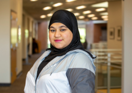 Phoenix College student Sally Alsigab stands on the second floor for Fannin Library on Campus. She is wearing a black hijab and althletic jacket. 