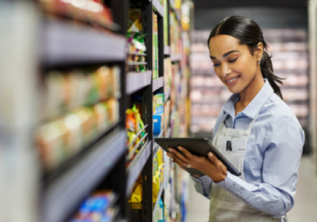 A grocery store staff holds a clipboard in the grocery aisle. 